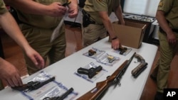 FILE - New York police officers pack a collection of illegal guns after a gun buyback event in Brooklyn, May 22, 2021.