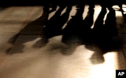 FILE - Shadows of laborers cast on the floor after an event for workers at a residential camp for laborers and managers, in Abu Dhabi, United Arab Emirates, April 6, 2016.