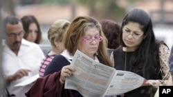 Voters read the a sample ballot as they wait in line to cast their vote in Hialeah, Florida, November 6, 2012.