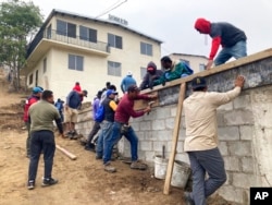 FILE - Migrant volunteers build a soccer field at Templo Embajadores de Jesus, Tijuana's largest migrant shelter, in Tijuana, Mexico, Oct. 13, 2022.