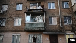 A resident repairs a broken window in an apartment building that was damaged by a Russian strike in Kyiv, Ukraine, Dec. 31, 2022.