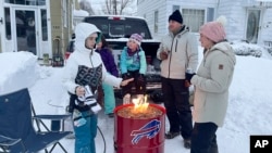 A group of neighbors gather around a fire pit on Culver Road after clearing snow in Buffalo, New York, Dec. 26, 2022. The region is digging out from a pre-Christmas blizzard that delivered hurricane-force winds and more than 4 feet of snow. 