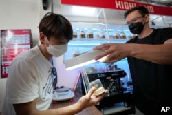 FILE - A customer views samples of marijuana before making a purchase at the Highland Cafe in Bangkok, Thailand, June 9, 2022.