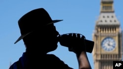 FILE - A tourist takes a drink opposite the Elizabeth Tower also known as Big Ben in London, Aug. 11, 2022.