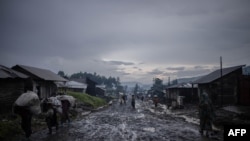 Après la pluie, des commerçants quittent le marché avec leurs bagages à la dot à Kitshanga, à 90 kilomètres de la ville de Goma dans l'est de la République démocratique du Congo le 10 décembre 2022.