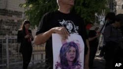 FILE - Protesters hold posters for slain Palestinian-American journalist Shireen Abu Akleh near the Augusta Victoria Hospital in east Jerusalem ahead of a visit by U.S. President Joe Biden, July 15, 2022.