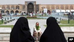 FILE- Iranian women pass a tourist in Isfahan some 400 kilometers south of Tehran, Iran, May 10, 2006. 