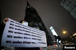 A person attends a vigil in protest of China's coronavirus disease restrictions, as people commemorate the victims of a fire in Urumqi, in Cologne, Germany, Nov. 30, 2022.