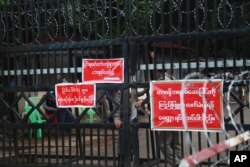 FILE - Police officers and prison personnel are seen behind the entrance gate of Insein prison in Yangon, Myanmar, Oct. 18, 2021.