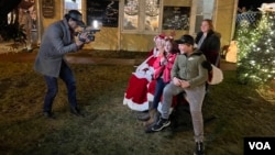 A family sits with Santa and Mrs. Claus outside the Grove Cafe & Bakery in Petersburg, W.Va., as VOA’s Saqib Ul Islam videotapes the encounter.