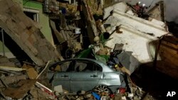Emergency workers clear the rubble after a Russian rocket hit a multistory building leaving many people under debris in the southeastern city of Dnipro, Ukraine, Jan. 15, 2023.