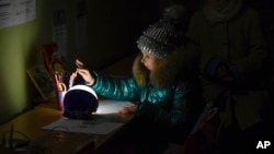 Alexandra, 11, draws at a school building, a "Point of Invincibility," a government-built help station that allows to charge phones with help of generators, serves food, drinks and the possibility to warm up, in Kramatorsk, Ukraine, Dec. 5, 2022.
