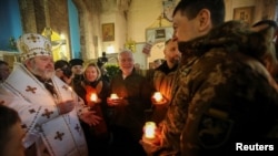 A priest of the Orthodox Church of Ukraine speaks with Ukrainian servicemen after a Christmas service in the Church of St. John the Theologian in Kharkiv, Dec. 25, 2022. 