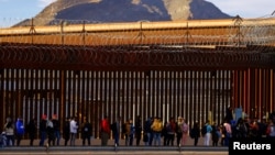 FILE - After crossing the Rio Bravo River, migrants queue near U.S.-Mexico border fence to request asylum in El Paso, Texas, Jan. 5, 2023. 