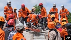 Rescuers use a saw as they try to recover the body of an earthquake victim from under the rubble of a collapsed building in Cianjur, West Java, Indonesia, Nov. 22, 2022. 