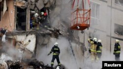 Emergency personnel evacuate a woman at the site where an apartment block was heavily damaged by a Russian missile strike in Dnipro, Ukraine, Jan. 15, 2023. 