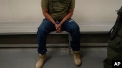 FILE - An immigrant considered a threat to public safety and national security waits to be processed by U.S. Immigration and Customs Enforcement agents at the ICE Metropolitan Detention Center in Los Angeles, after an early morning raid, June 6, 2022.
