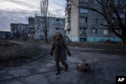 Svetlana, 57, hauls a cart of supplies in the Staryi-Saltiv, Kharkiv region of Ukraine, Dec. 29, 2022. The community has been living without running water and electricity for more than 6 months.