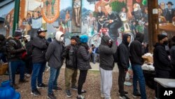 Migrants form a line to receive warm food donated by residents in El Paso, Texas,, Dec. 18, 2022.