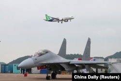 珠海航空展上展示的C-919远航大型客机在一架中国空军战机上空飞过。（2022年11月8日）