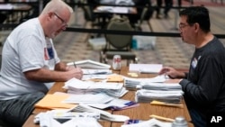 Petugas pemilu AS menghitung surat-surat suara lewat pos di Milwaukee, Wisconsin di mana persaingan antara kandidat partai Demokrat dan Republik berlangsung sangat ketat (8/11). 