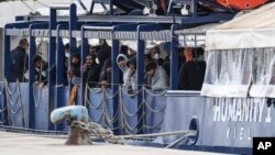 Migrants stand on the deck of the Humanity 1 rescue ship run by the German organization SOS Humanitarian at harbor in the port of Catania, Sicily, southern Italy, Nov. 6, 2022. 