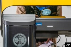 A senior voter uses his own magnifying glass while casting his ballot at a participating Flex Voting Center at the offices of the Coalition for Humane Immigrant Rights, CHIRLA, in Los Angeles, Nov. 5, 2022.