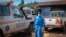 A man wearing protective clothing carries water to wash the interior of an ambulance used to transport suspected Ebola patients, in the town of Kassanda, Uganda, Nov. 1, 2022.