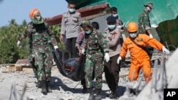 Rescuers carry the body of an earthquake victim recovered from debris of a collapsed mosque in North Lombok, Indonesia, Aug. 7, 2018.