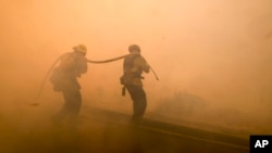 Firefighters battle a fire along the Ronald Reagan (118) Freeway in Simi Valley, California, Nov. 12, 2018.