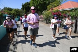 Sukarelawan untuk capres oposisi dan wapres saat ini, Leni Robredo, membagikan brosur kepada warga selama kampanye dari rumah ke rumah di kota Pasuquin, provinsi Ilocos Norte, Filipina, 26 Maret 2022. (Foto; Ted ALJIBE / AFP)