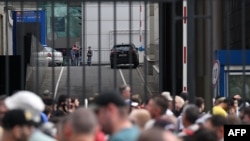 FILE - Police officers (background) secure an area as people and office workers stand in line to enter a building of Expocentre following a drone attack in Moscow on Aug. 18, 2023.