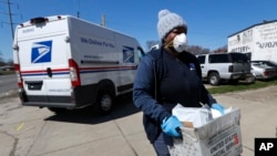 FILE - A U.S. postal worker makes a delivery in Warren, Mich., April 2, 2020. 
