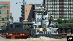 A small, but mighty, tugboat pushes a barge loaded with coal up the Ohio River, past downtown Louisville, Kentucky.