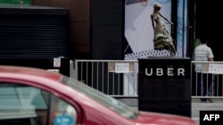 A taxi passes by an Uber station outside a shopping mall in Beijing on August 1, 2016.