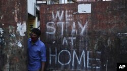 FILE - An Indian wearing a face mask looks out from a gate during lockdown to prevent the spread of new coronavirus in Hyderabad, India, April 18, 2020.