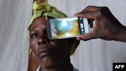 FILE - A technician scans the eye of a woman with a smartphone application, in Kianjokoma village, near Kenya's lakeside town of Naivasha, Aug. 28, 2013.