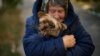 A woman warms her dog in Kivsharivka, Ukraine, Oct. 16, 2022. As temperatures drop in Ukraine, those who haven't fled the Russian occupation are on the threshold of winter. The UNHCR has launched a global campaign to help people displaced by war and persecution survive winter.
