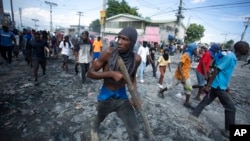 FILE - A protester carries a piece of wood simulating a weapon during a protest demanding the resignation of Prime Minister Ariel Henry, in the Petion-Ville area of Port-au-Prince, Haiti, Oct. 3, 2022.