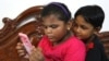 Two elementary school students are seen captivated by a mobile phone, Oct. 11, 2022. School children used mobile phones to study online during the COVID lockdowns in India and many of them have now turned into what some call "mobile phone addicts."