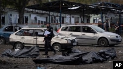 A Ukrainian police officer walks past bags containing the bodies of people who died in a Russian missile attack, in the city of Zaporizhzhia, Ukraine, Sept. 30, 2022. Russia now claims territories it holds in Ukraine's Zaporizhzhia region as its own.
