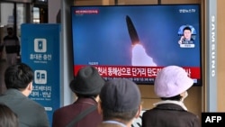 People watch a television screen showing a news broadcast with file footage of a North Korean missile test, at a railway station in Seoul on October 28, 2022, after North Korea fired two short-range ballistic missiles according to South Korea's military. 