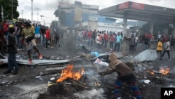 Demonstrators mill around a barricade set up to protest against fuel price hikes and to demand that Haitian Prime Minister Ariel Henry step down, in Port-au-Prince, Haiti, Sept. 19, 2022.