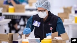 FILE - A technician prepares a Pfizer vaccine at a COVID-19 vaccination site in Sydney, Australia, May 10, 2021.