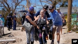 Rescuers help evacuate Suzanne Tomlinson, a resident who rode out the storm, as they carry her to a waiting boat in the aftermath of Hurricane Ian on Pine Island in Florida's Lee County, Oct. 2, 2022. 