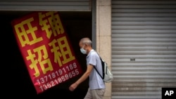 一名男子走过北京街头一家招租的商铺。（2022年8月17日）