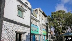 People walk next to the damaged Tawakal hotel after it was attacked Sunday by militants in the port city of Kismayo, in southern Somalia, Oct. 24, 2022..