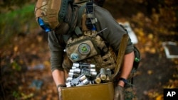 A Ukrainian territorial defense deminer takes Russian ammunition left behind as his team clears mines near Hrakove village, Ukraine, Oct. 13, 2022.
