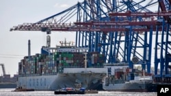 FILE -- Port cranes load container ships at the import and export harbor in Hamburg, Germany, March 19, 2022.
