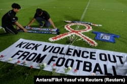 Suporter klub sepak bola memasang atribut Arema saat berjaga di Stadion Kapten I Wayan Dipta, usai terjadi kerusuhan dan penyerbuan di Stadion Kanjuruhan usai pertandingan sepak bola antara Arema vs Persebaya Surabaya. (Foto: Antara/Fikri Yusuf via Reuter